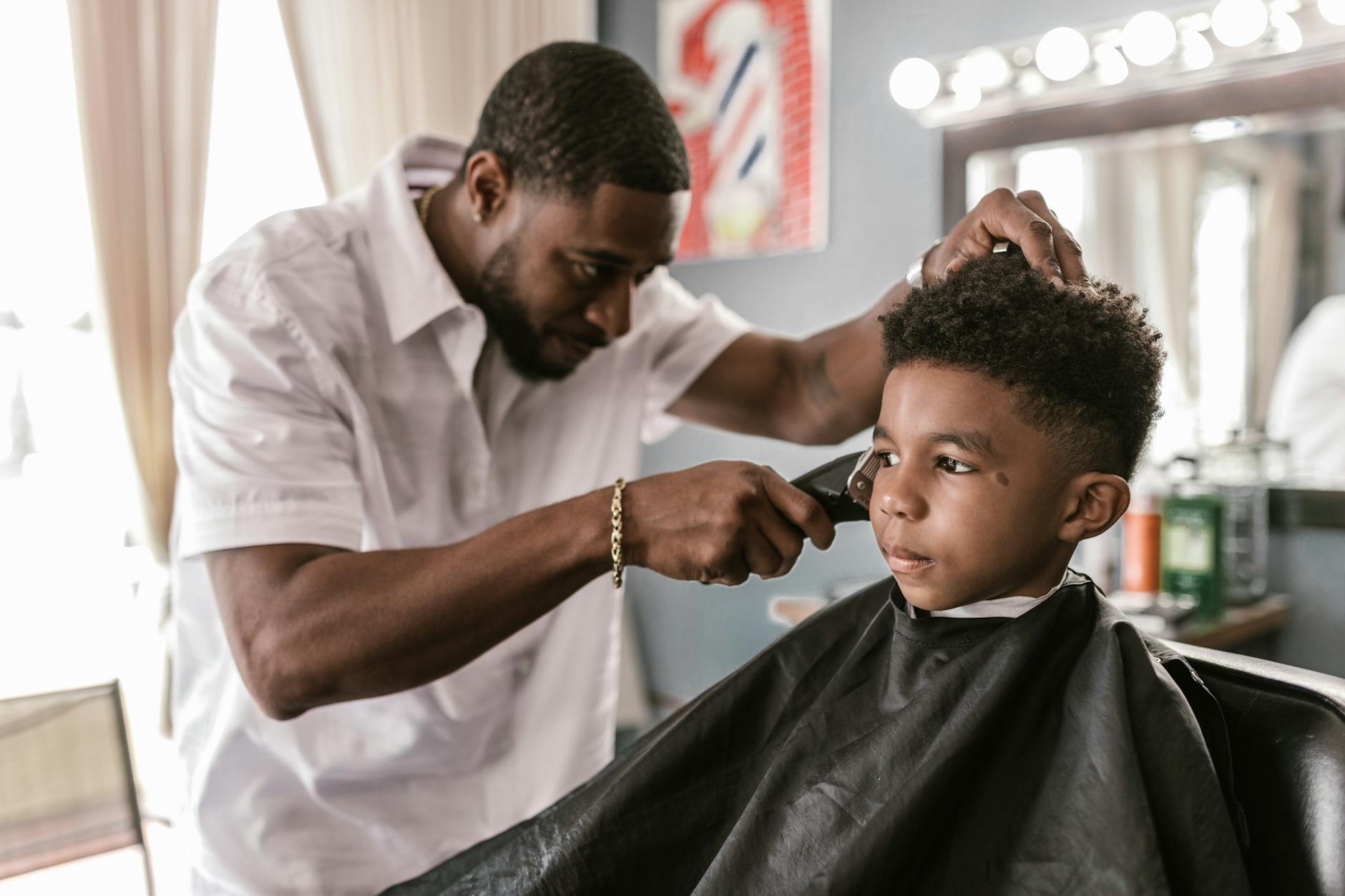 a barber holding a hair clipper trimming a boy s hair