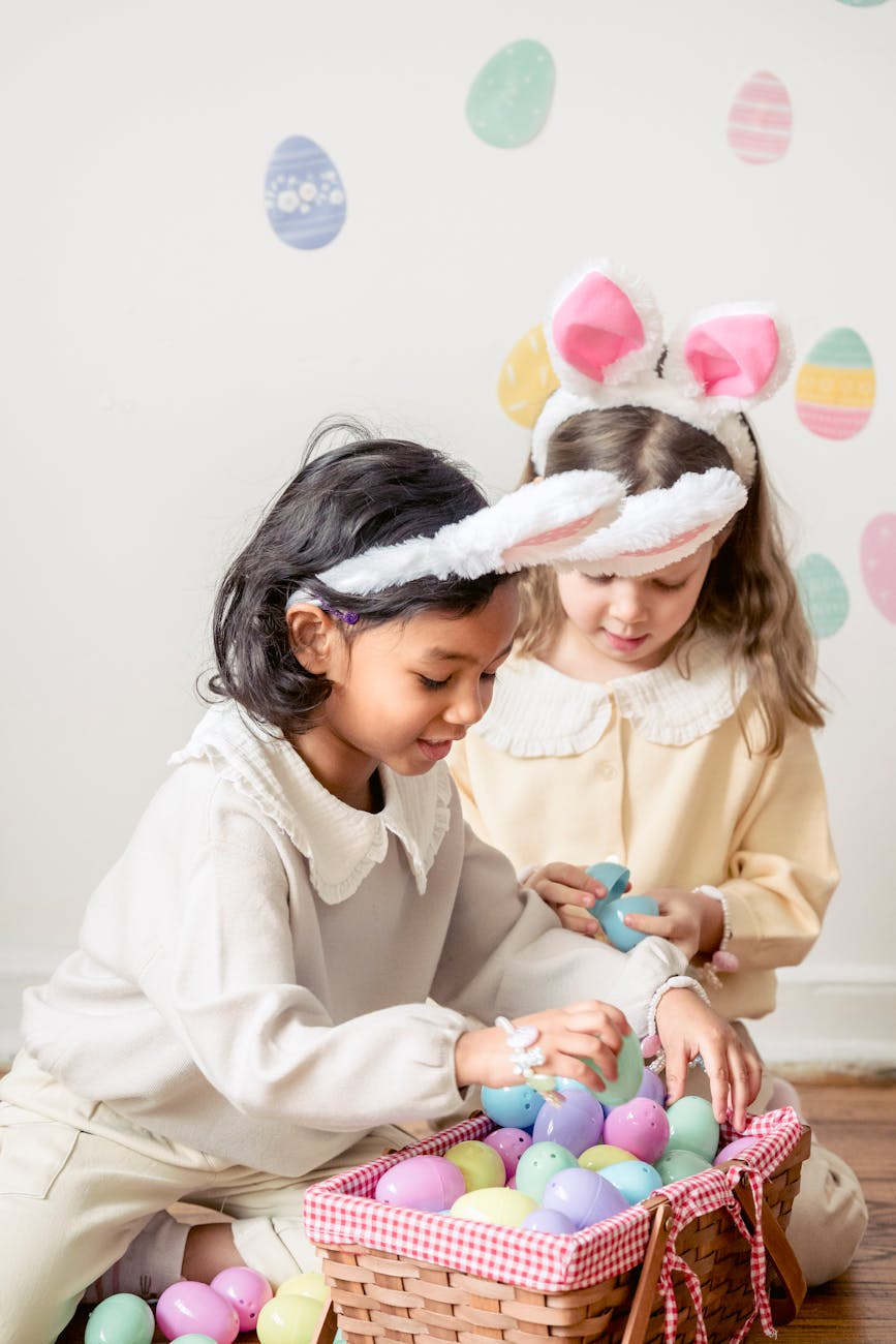 curious diverse little girls choosing easter eggs placed in wicker basket