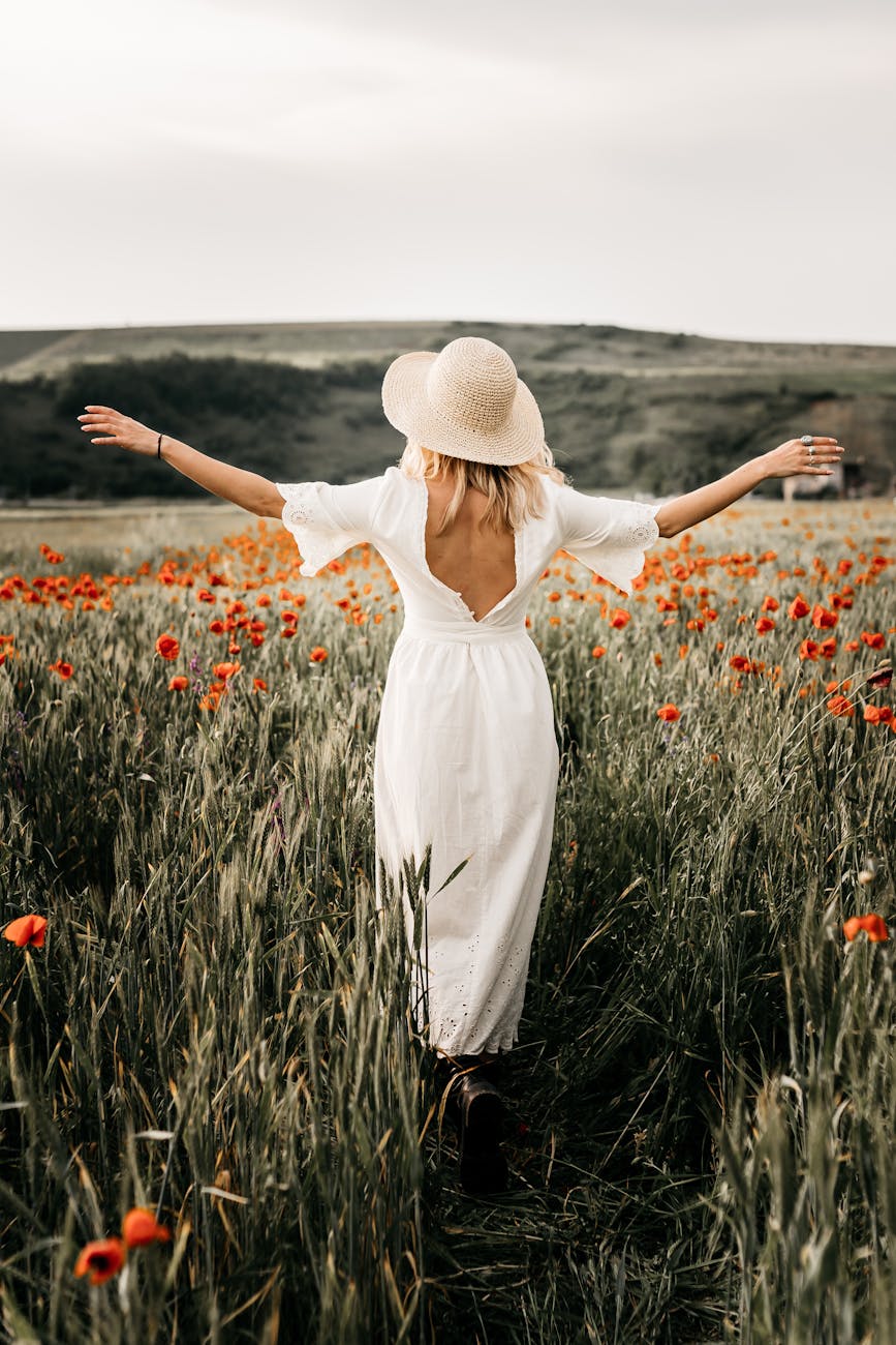 elegant woman in hat walking in field with flowers